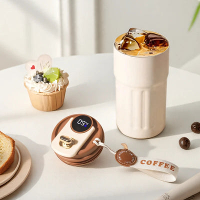 Inteligentny kubek termiczny 450 ml z wyświetlaczem temperatury, na stole obok ciasta i akcesoriów kawowych.